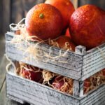 Fresh ripe Sicilian oranges in a wooden box on an old background. Selective focus.