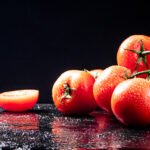 Ripe tomatoes on a branch and tomato halves. On a black background. High quality photo